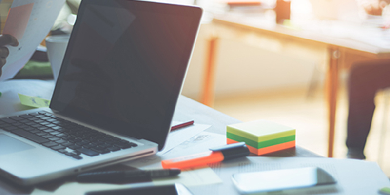 Laptop sitting on desk with highlighter and sticky notes
