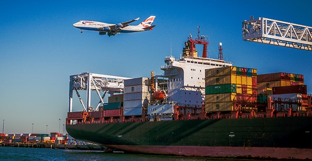 Plane flying over a container ship