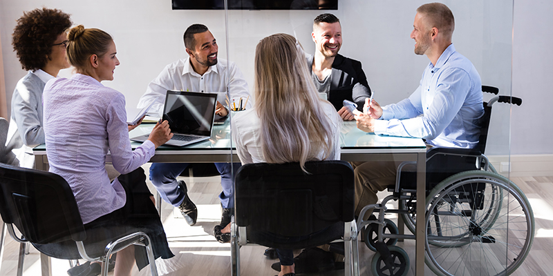 Disabled Male Manager Sitting With His Colleagues At Workplace