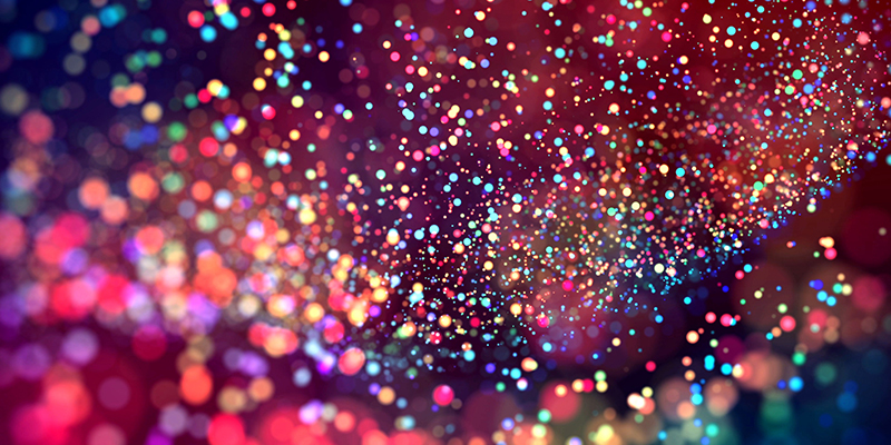 a cloud of multicolored particles in the air like sparkles on a dark background with a small depth of field