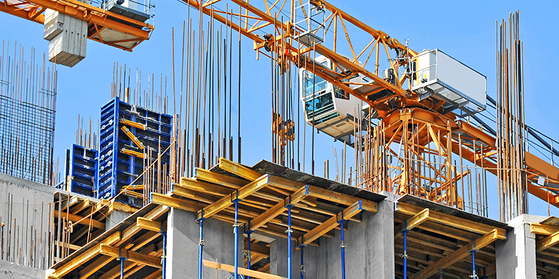 Crane and building construction site against blue sky