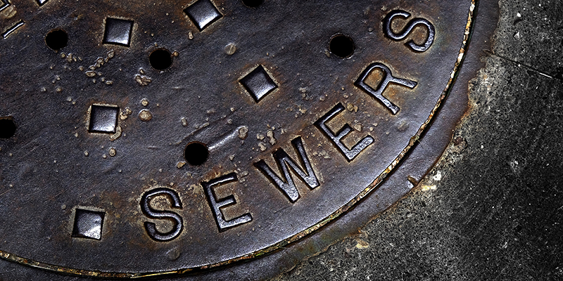 Man hole cover for sewer entry with iron grate on street in a city