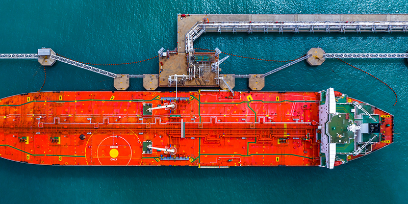 Aerial top view of fuel tanker ship at the port, Oil terminal is industrial facility for storage of oil and gas petrochemical products ready for transport to further storage facilities.