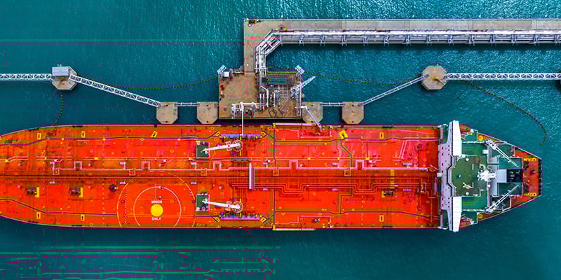 Aerial top view of fuel tanker ship at the port, Oil terminal is industrial facility for storage of oil and gas petrochemical products ready for transport to further storage facilities.