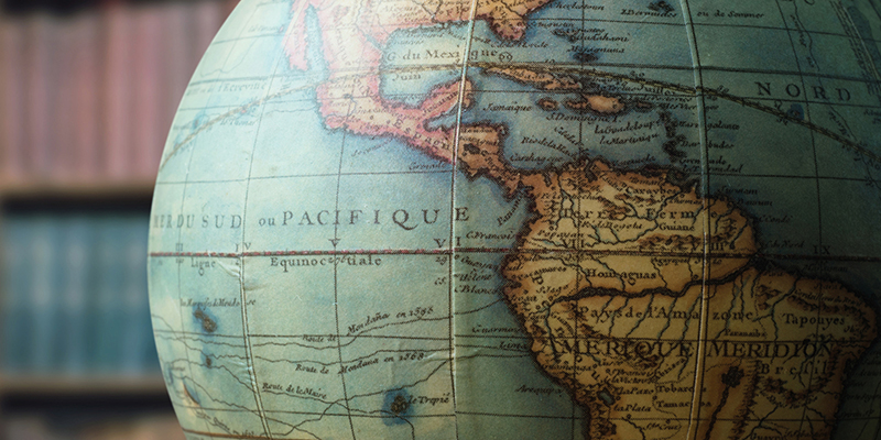 Old globe on bookshelf background. 