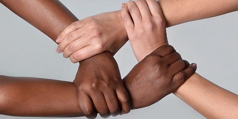 white Caucasian female hands and black African American holding together in world unity and racial love and understanding in tolerance and races diversity cooperation concept