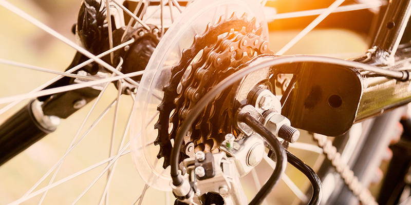 Close up of a Bicycle wheel with details, chain and gearshift mechanism, in morning sunlight.