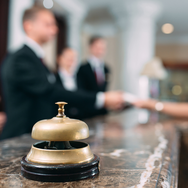 Picture of guests getting key card in hotel; focus on bell on counter