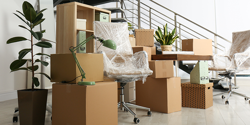 Cardboard boxes and furniture near stairs in office. Moving day