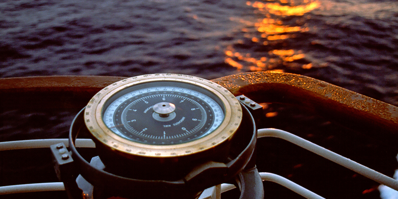 Ships compass with sunset in background.