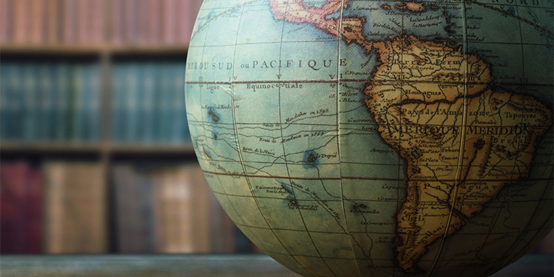 Globe in focus with a vintage bookshelf out of focus
