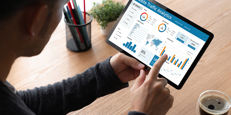 Person holding a tablet reviewing charts and graphs
