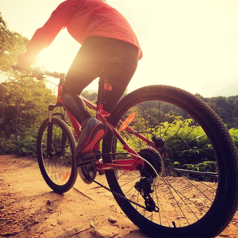 Person riding a mountain bike with the sun in the distance