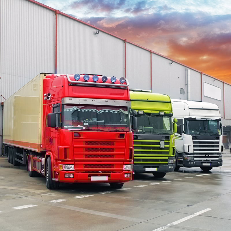 Three trucks parked outside of a warehouse