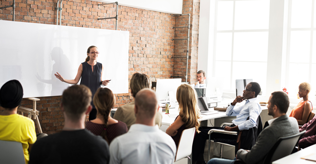 Woman leading meeting in front of a dry-erase board