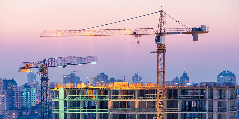 Building cranes at construction site at night