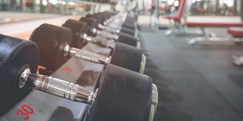 Close up of many metal dumbbells on rack in sport fitness center.