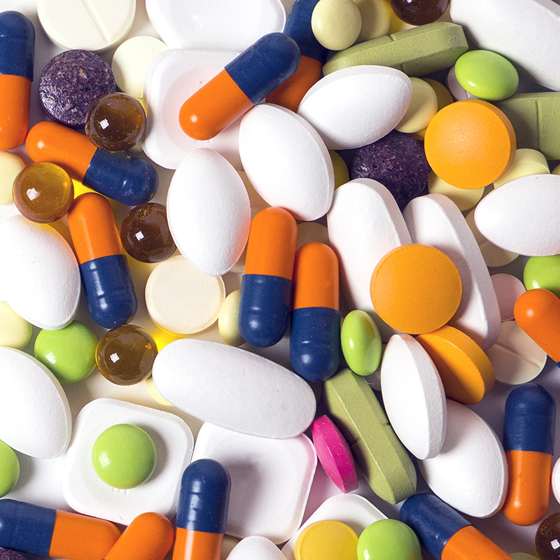 a lot of multicolored pills and capsules on the white background with copy space