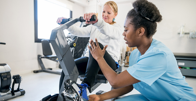 Nurse helping patient on exercise bike