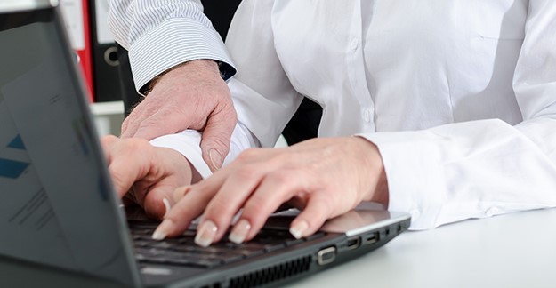 Man touching woman's wrist while she types on laptop